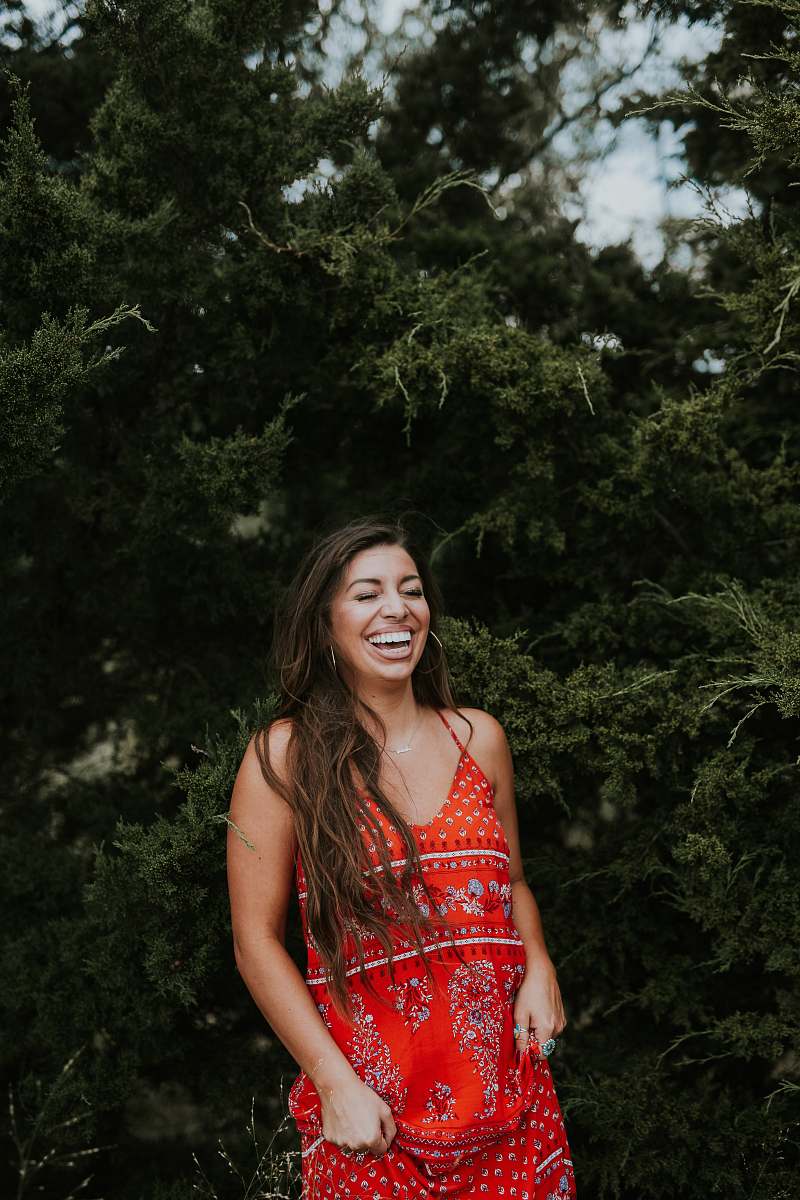 evening dress woman laughing while standing near tree robe